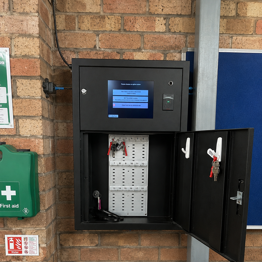 A black metal electronic lockbox security cabinet mounted on a brick wall, with its door open to reveal a white card reader slot and a blue display screen on the front.